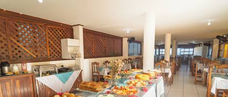 A buffet with a variety of food items and a seating area with tables and chairs.
