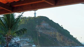 A beach with umbrellas, palm trees, and a lifeguard tower. - Brisa do Caita Praia Hotel (Cairu)