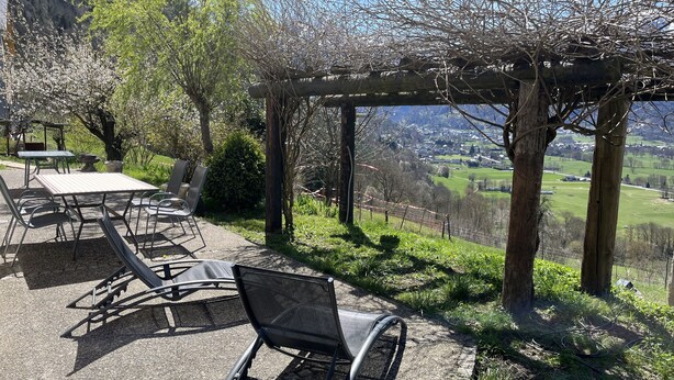 An outdoor seating area with tables and chairs, a pergola, and a view of a valley. - Maison à Camparan Proche de Saint-lary (Camparan)
