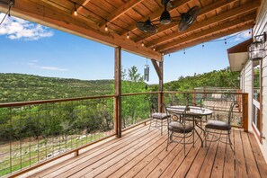 A wooden deck with a table and chairs, overlooking a mountainous landscape. - Painted Paradise Main House I Private Pool I Lake Nearby (New Braunfels)