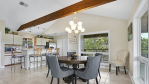 Zona pranzo con soffitto in legno, un lampadario e vista sull'esterno.