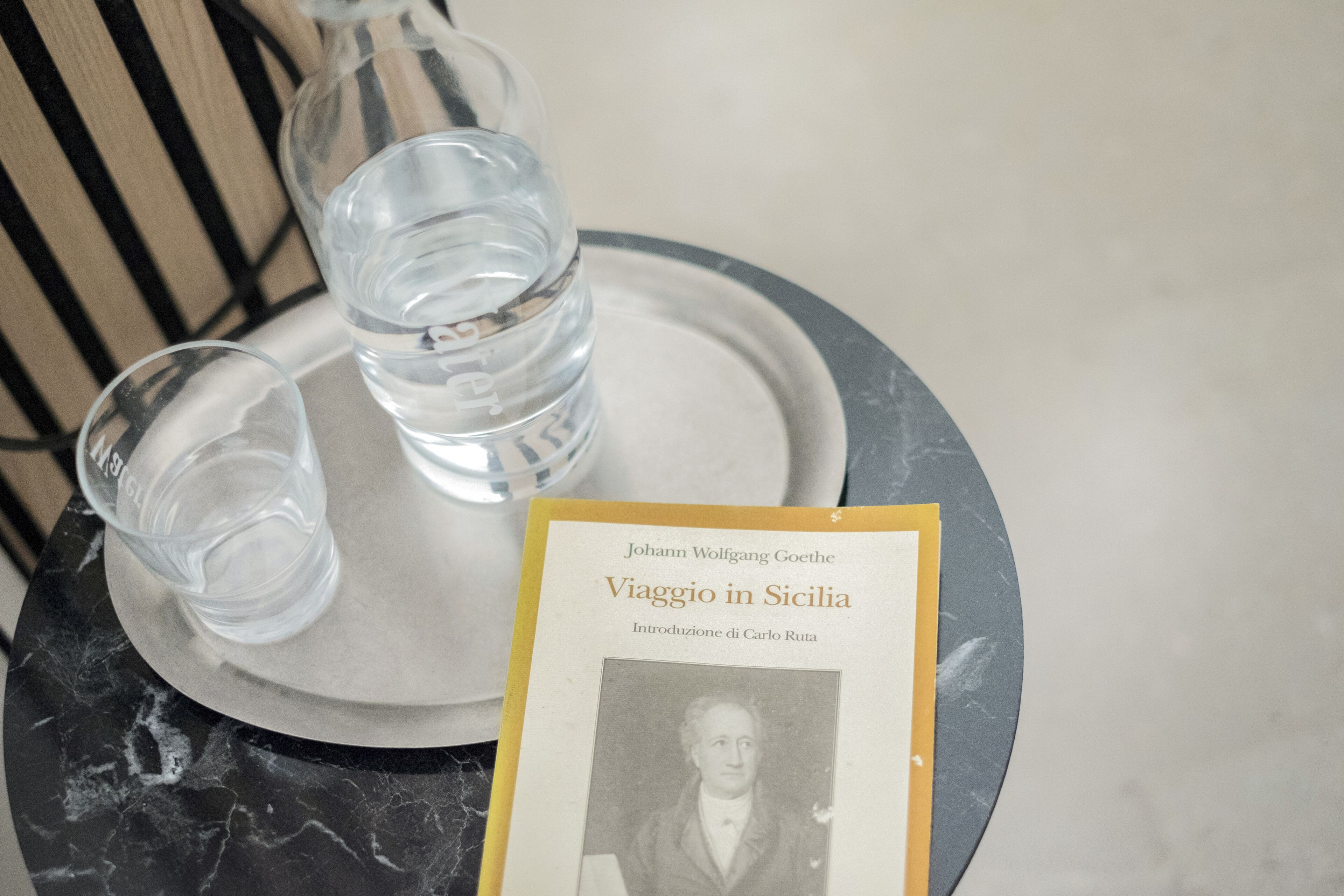 A tray with two glasses of water and a book titled 'Viaggio in Sicilia' by Johann Wolfgang Goethe.