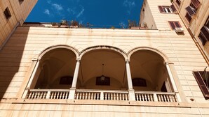 Un bâtiment doté de trois fenêtres en arc de cercle et d’un balcon orné de balustrades.