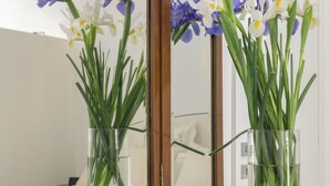 Une coiffeuse en bois avec un miroir, un livre et deux vases en verre ornés de fleurs.