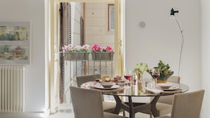 Un coin repas avec une table ronde, quatre chaises et un balcon agrémenté de fleurs.