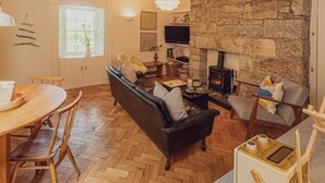 Un salon chaleureux avec un mur en pierre, une cheminée, un canapé et un coin repas agrémenté de meubles en bois.