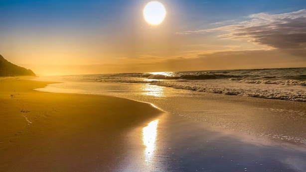 Una playa con mar tranquilo y cielo despejado.