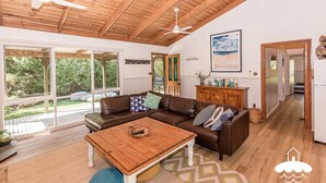 Un salón espacioso con un sofá de cuero marrón, una mesa de centro de madera y un amplio ventanal con vistas al exterior.