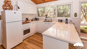 Una cocina moderna con armarios blancos, encimera de madera y un amplio ventanal con vistas al exterior.