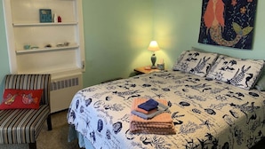 Une chambre à coucher comprenant un lit, une chaise, une étagère et un tableau mural.