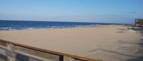 A beach with a wooden fence and a building in the background.