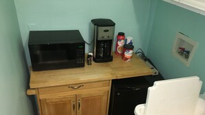 Une cuisine compacte équipée d’un four à micro-ondes, d’une machine à café et de placards de rangement.