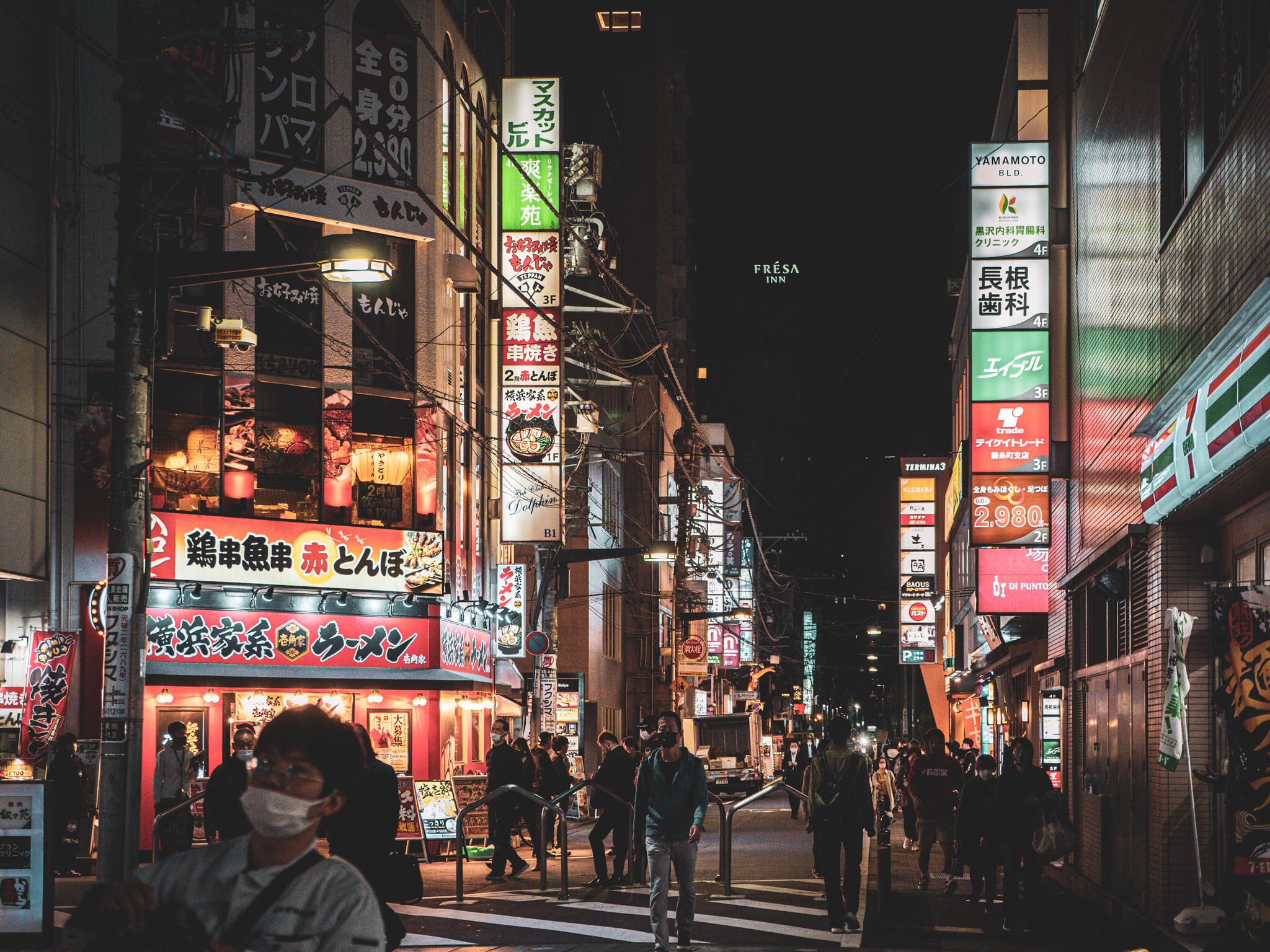 A busy urban street at night with illuminated signs and buildings.