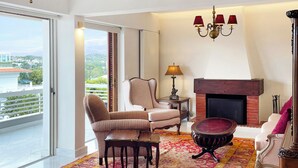 A spacious living room with a large window, a fireplace, and a chandelier. - A unique 3 level penthouse with a great sea view to Vouliagmeni Bay (VOULIAGMENI)