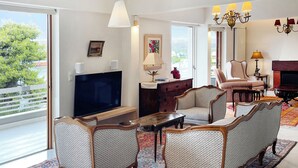 A spacious living room with a large window, a flat-screen TV, a coffee table, and a patterned rug. - A unique 3 level penthouse with a great sea view to Vouliagmeni Bay (VOULIAGMENI)