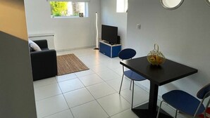 Un salon moderne avec un canapé, une table à manger et des chaises, un téléviseur et une petite fenêtre.