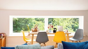 Une pièce dotée d’une grande fenêtre, d’une table à manger avec des chaises et d’un canapé avec des coussins.