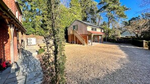 Une maison à deux étages avec une allée en gravier, un porche couvert et un escalier en bois menant au deuxième étage.