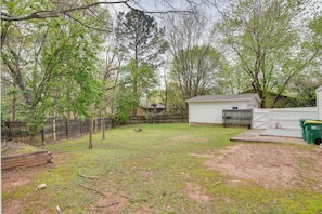 Enjoy the serene atmosphere of this spacious backyard with a mix of grassy areas and trees.