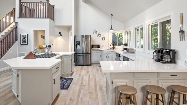 A modern kitchen with a central island, stainless steel appliances, and a staircase leading to an upper level. - 20 Acres + Pool + Game Room | Paso Wine Country | Oaks and Roses Ranch (Paso Robles)