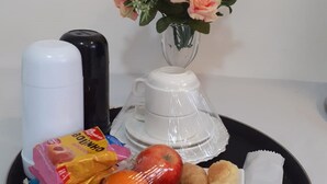 Un plateau contenant des aliments, une cafetière blanche, une bouilloire électrique noire et un vase avec des fleurs.