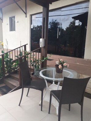 A glass-top table with two chairs, a small potted plant, and a view of a residential area.