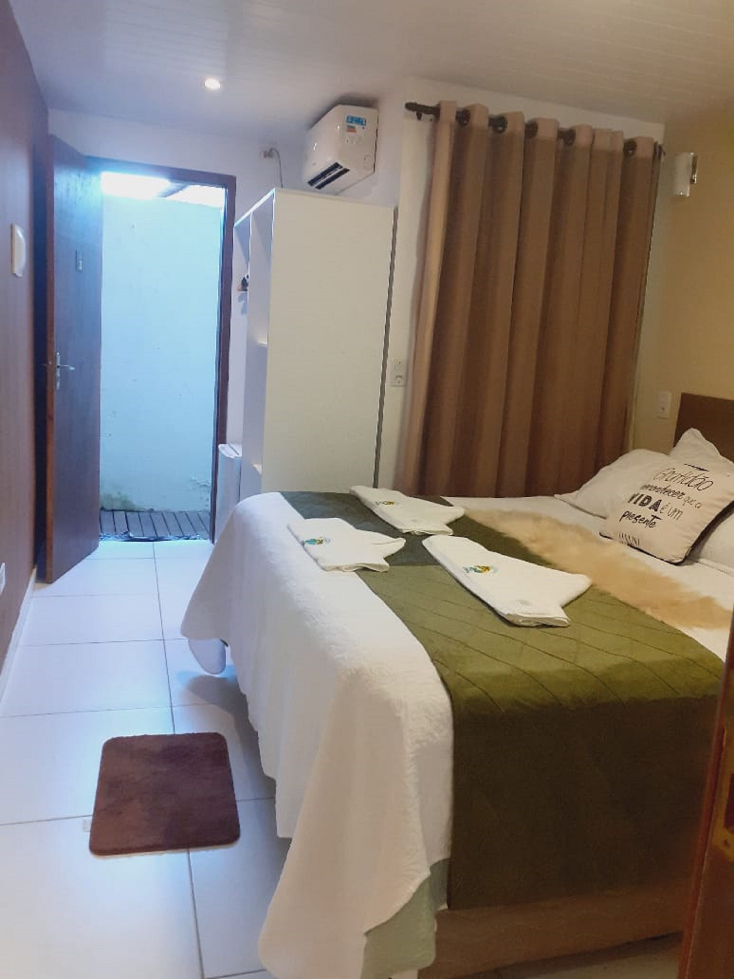 Habitación de hotel con una cama, un tapete marrón, un equipo de aire acondicionado blanco y una puerta que da al exterior.