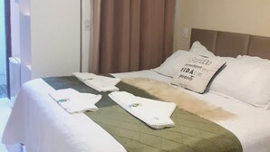 Une chambre d’hôtel avec un lit, une couvre-lit verte, des oreillers blancs et un rideau marron.