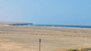 Un paysage plat et désolé, avec une falaise lointaine et quelques véhicules.