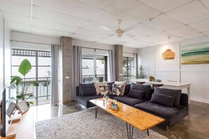 Een moderne woonkamer met een bank, salontafel en grote ramen.