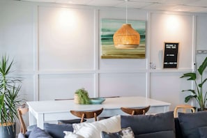 Un interior moderno con zona de comedor, un sofá y una lámpara colgante.