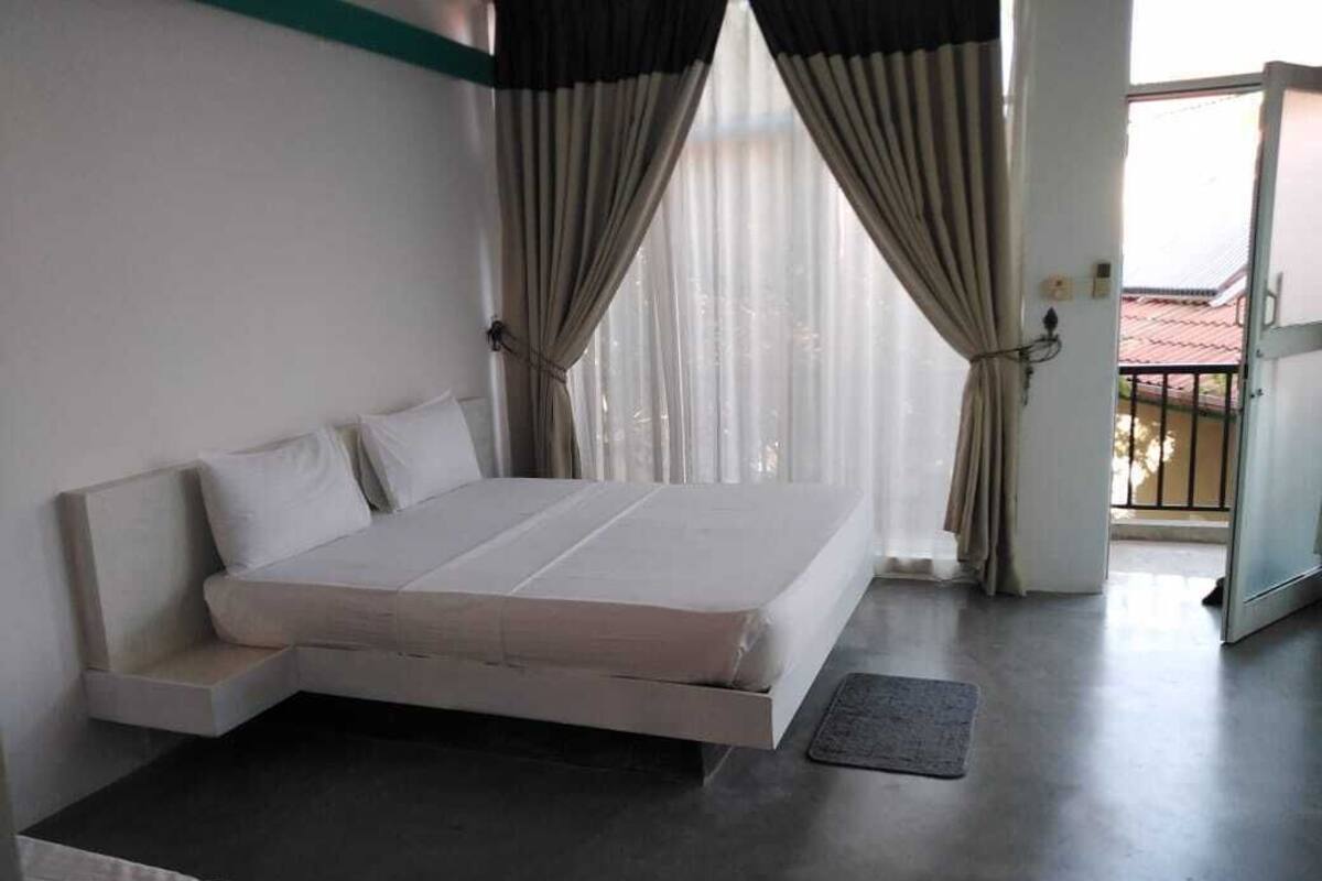 A bedroom with a bed, a bench, and a view of the outside.