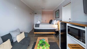 A modern bedroom with a bed, bedside table, and a built-in microwave. - Yamba Views Room 11 (Yamba)