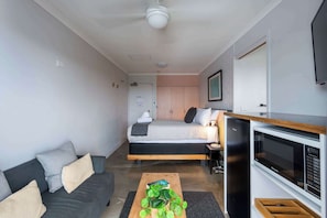 A modern bedroom with a bed, bedside table, and a built-in microwave. - Yamba Views Room 11 (Yamba)