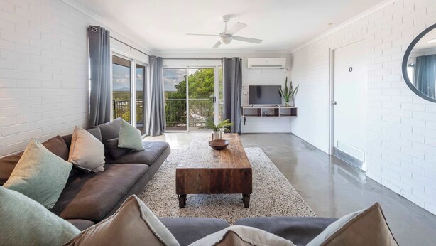 A modern living room with a sofa, coffee table, and a ceiling fan. - Yamba Views Apartment (Yamba)