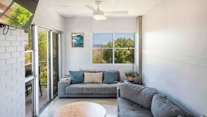 A modern living room with a grey sofa, a wooden coffee table, and a ceiling fan.