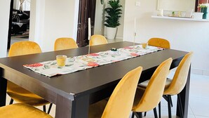 Een eetgedeelte met een donker houten tafel, gele stoelen en een hanglamp.