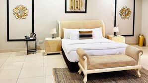 Een moderne slaapkamer met een groot bed, een kroonluchter en twee kunstwerken in lijsten.