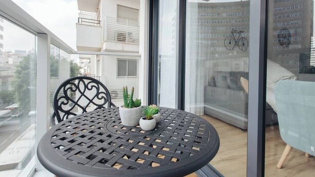 Ein Balkon mit rundem Tisch, zwei Topfpflanzen und einem Stuhl.