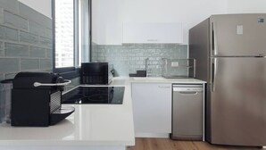 Eine moderne Küche mit weißen Schränken, einem Edelstahlkühlschrank, einer Kaffeemaschine und einem Geschirrspüler.