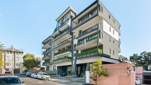 A multi-story building with balconies, a parking area, and a clear sky. - Designer Apartment in Sea Point (Cape Town)