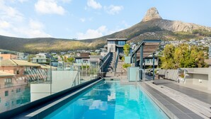 A swimming pool with a view of a mountain and residential buildings in the background. - Designer Apartment in Sea Point (Cape Town)