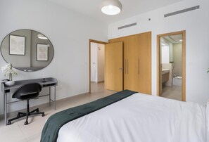 Ein Schlafzimmer mit Bett, Schreibtisch, Stuhl, Spiegel und Kleiderschrank.