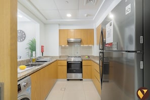A modern kitchen with wooden cabinets, stainless steel appliances, and a built-in oven. - 
Vogue, Downtown Bellevue Towers near Burj Khalifa and Dubai Mall (دبي)