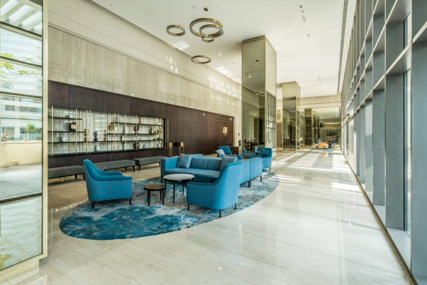 A modern lobby with a seating area, a wall with decorative items, and a glass partition.
