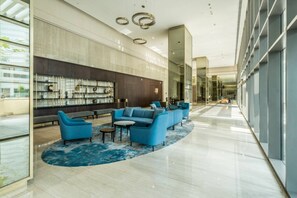Eine moderne Lobby mit Sitzgelegenheit, einer Wand mit Dekoration und einer Glasabtrennung.