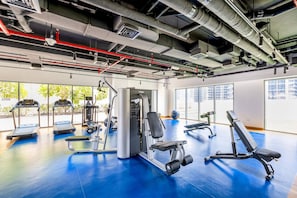 Ein Fitnessstudio mit Laufbändern, Kraftgeräten und einem blauen Boden.