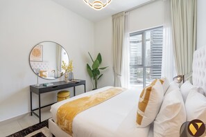 A modern bedroom with a bed, a bedside table, a mirror, and a window with curtains.