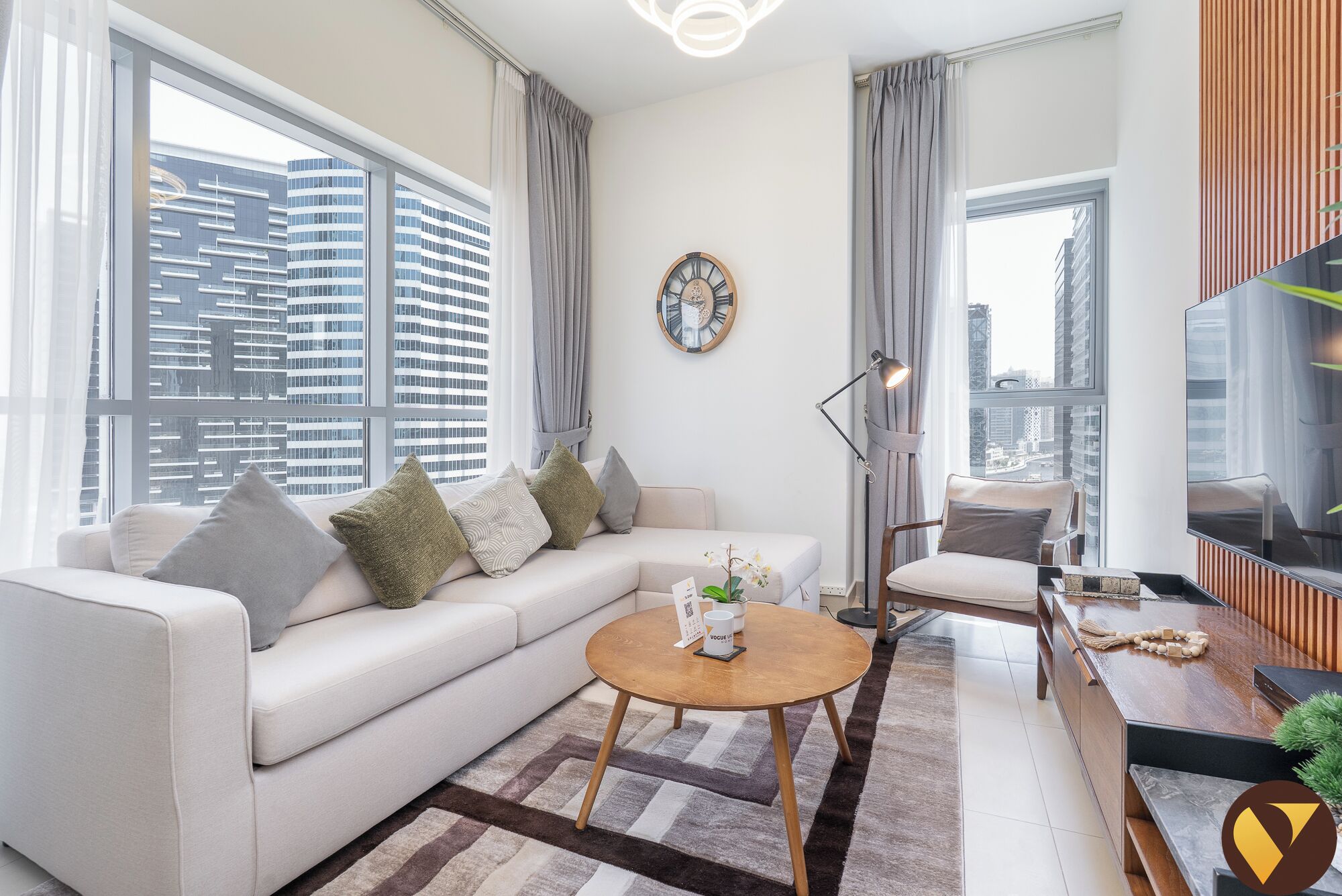 A modern living room with a sofa, a coffee table, a TV, and a city view through large windows.