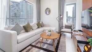 A modern living room with a sofa, a coffee table, a TV, and a city view through large windows.